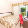 Camera con letto matrimoniale, sedia rossa, TV e porta finestra che si affaccia sul giardino.