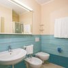 Bagno con lavabo, bidet, wc e pareti piastrellate turchesi.