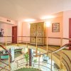 Corridoio d'hotel con scale curve, porte rosse e mobili antichi.