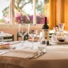 Tavola apparecchiata con bottiglia di vino e decanter in un ristorante luminoso.