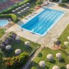 Vista dall'alto di una piscina, area solarium con ombrelloni e un campo da tennis.