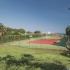 Campo da tennis recintato con vista sul mare e circondato da alberi.