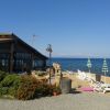 Terrazza vista mare con lettini e ombrelloni vicino a un edificio in legno.