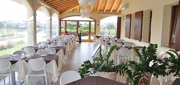Sala da pranzo luminosa con tavoli apparecchiati e piante decorative.