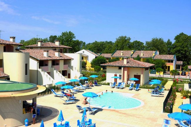 Un complesso con piscina, sedie a sdraio e ombrelloni.