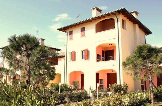 Edificio residenziale con giardino e alberi.
