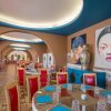 Vista interna di un ristorante con sedie rosse e decorazioni artistiche sulle pareti.