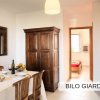 Sala da pranzo con tavolo, sedie e armadio in legno.