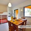 Cucina luminosa con tavolo apparecchiato, letto a castello e finestra aperta su un giardino.