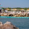 Spiaggia con lettini, tettoie e rocce sul mare.