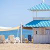 Spiaggia con cabina blu, lettini e vista mare.