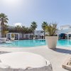 Piscina con palme e grandi vasi bianchi. Seduta in primo piano.