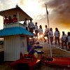 Persone in uniforme si trovano su una torre di guardia in spiaggia al tramonto.
