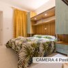 Interno di una camera per quattro persone con letto matrimoniale e letti a castello, tende dorate.