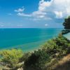 Mare blu con cielo nuvoloso e vegetazione verde sulla costa.