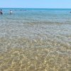 Spiaggia con mare limpido e persone che nuotano.