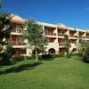 Complesso residenziale a tre piani con giardino e alberi verdi.
