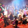 Un gruppo di persone che posa entusiasta su un palco con sfondo colorato.