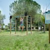 Una persona si esercita su una struttura da ginnastica all'aperto, circondata da alberi.