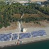 Vista aerea di una spiaggia con file di ombrelloni e vegetazione retrostante.