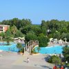 Una piscina con un ponte nel mezzo, circondata da alberi e lettini.
