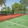 Campo da bocce all'aperto con due persone che giocano, circondato da alberi.