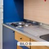 Angolo cottura con piano in acciaio inox, fornelli e frigorifero bianco.