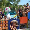 Gruppo di bambini e adulti in un parco giochi con un costume da panda sorridente.