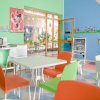 Sala colorata con tavolini e sedie per bambini, decorazioni murali vivaci e giochi.
