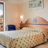 Camera da letto con letto matrimoniale e accesso a un balcone con sedie bianche.