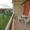 Balcone con tavolo e quattro sedie bianche, vista su un giardino e edifici.