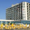 Hotel con molti balconi, circondato da sdraio gialle.