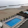Piscina e spiaggia con file di ombrelloni.