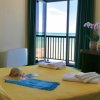 Camera con letto giallo e vista mare, fiori sul tavolo.