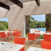 Zona pranzo all'aperto con sedie arancioni e tavoli bianchi, vista piscina.