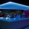 Bar notturno illuminato di blu con un bancone bianco lucido.