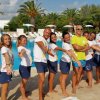 Gruppo di persone in divise estive, sorridenti, posano davanti a una piscina.