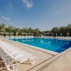 Lettini bianchi disposti attorno a una grande piscina all'aperto.