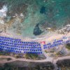 Vista aerea di una spiaggia con ombrelloni blu allineati.