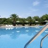 Piscina all'aperto con palme e ombrelloni bianchi.