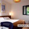 Camera con letto matrimoniale, finestra aperta e sedia blu. Scrivania con libri.