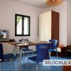 Soggiorno con tavolo da pranzo, sedie blu e televisore. Arredamento moderno.