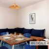 Angolo pranzo con tavolo apparecchiato, sedie blu e divano con grandi cuscini blu.