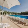Piscina esterna con lettini bianchi e ombrelloni.