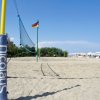 Spiaggia con rete da beach volley e ombrelloni.