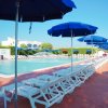 Ombrelloni blu e lettini bianchi vicino a una piscina.