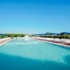 Piscina con sedie a sdraio e ombrelloni blu.