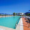 Piscina con ombrelloni blu sotto un cielo limpido.