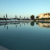 Piscina riflettente con ombrelloni e edificio sullo sfondo.