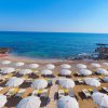 Ombrelloni bianchi su spiaggia sabbiosa, mare calmo.